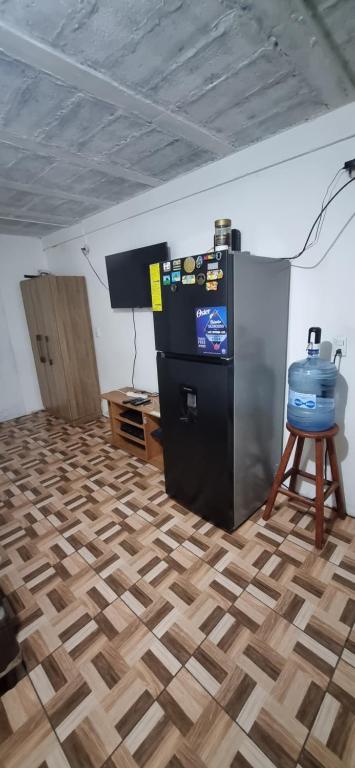 een kamer met een houten vloer en een zwarte koelkast bij apartamento pequeño amueblado in San Salvador