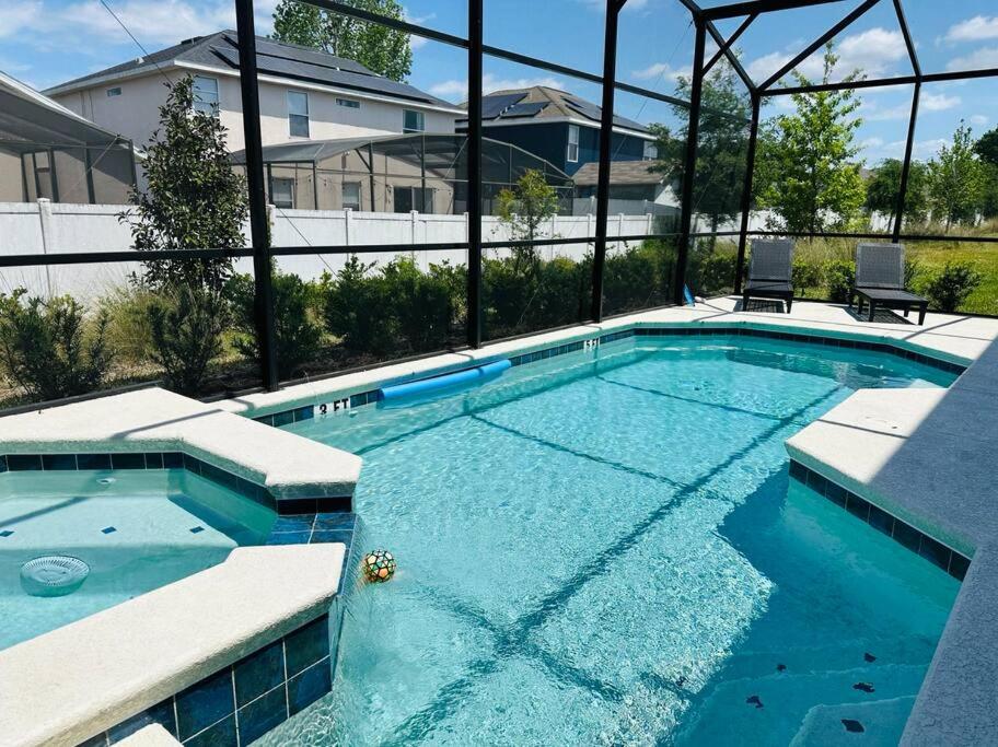une grande piscine d'eau bleue dans l'établissement Cozy 12BR Pool House/BBQ/Sleep 24/Near Disney, à Kissimmee