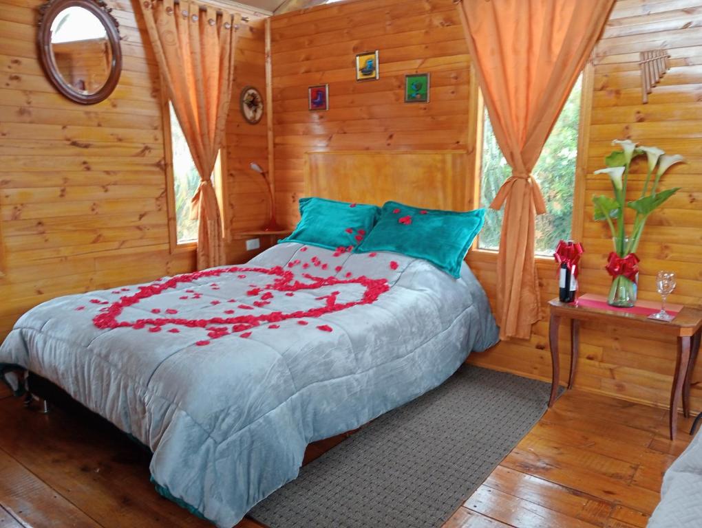 een slaapkamer met een bed met rode bloemen erop bij Cabaña Los Linos in Guasca