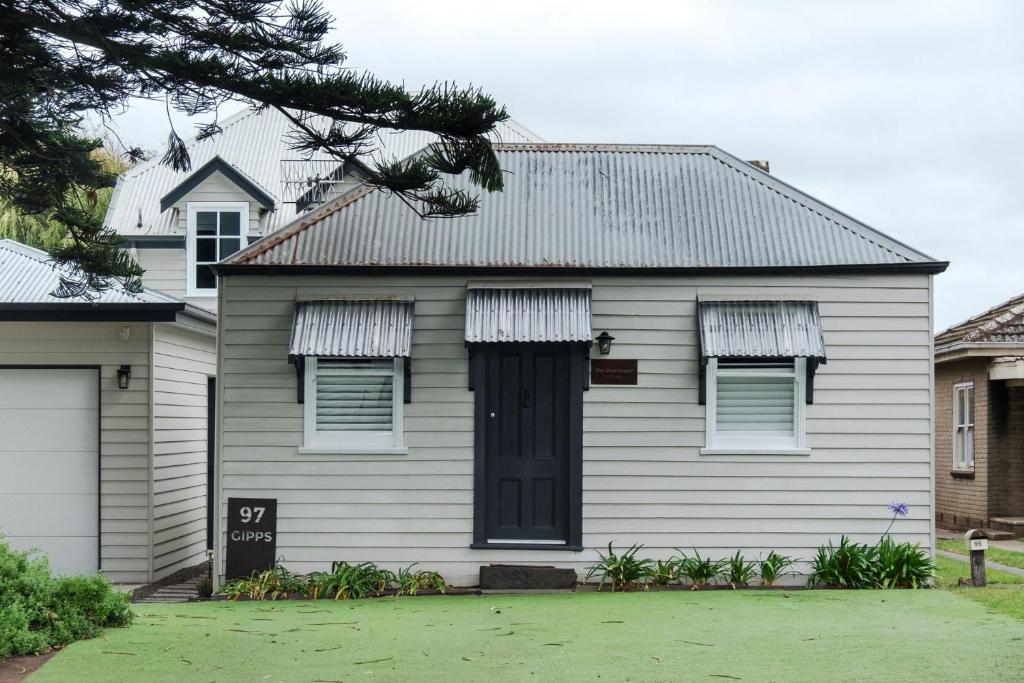 une maison blanche avec une porte noire dans l'établissement The Dog House Cottage, à Port Fairy