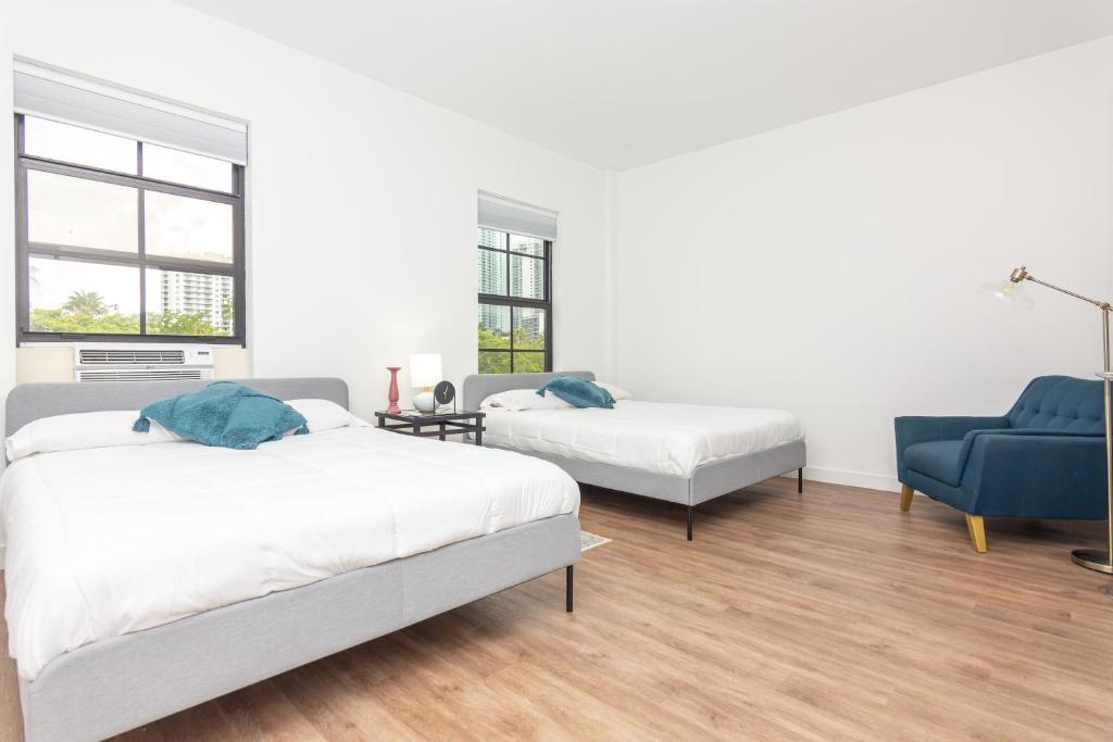 biały pokój z 2 łóżkami i niebieskim krzesłem w obiekcie Downtown Miami - 1 Bedroom Apartment - 5 minutes from Wynwood w Miami