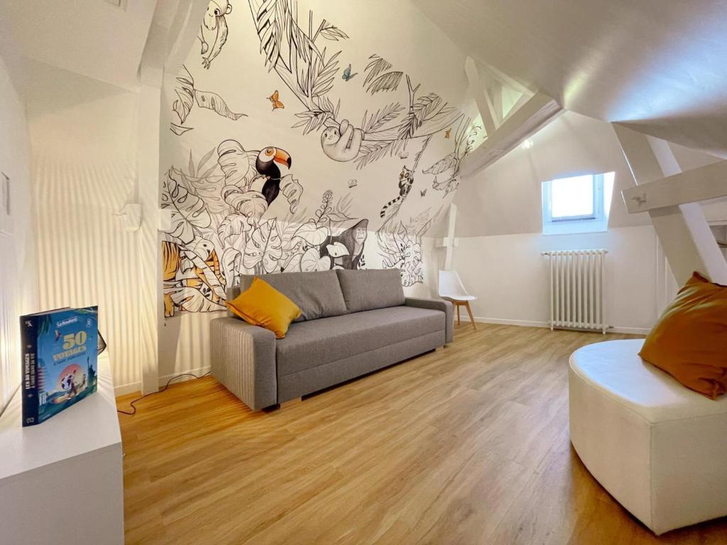 ein Wohnzimmer mit einer Couch und einem Wandgemälde in der Unterkunft Gîte tout confort pour 6-8 pers, cœur de village, parking privé, jardin clos, proche ZooParc de Beauval - FR-1-491-344 in Noyers-sur-Cher