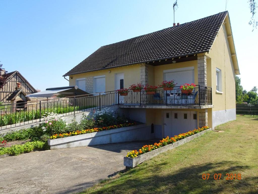 a house with a balcony with flowers on it at Gîte familial en Sologne : jardin, équipements enfants, vélos, proche Châteaux de la Loire - FR-1-491-348 in Dhuizon