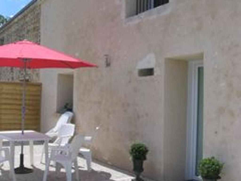 a patio with a table and a red umbrella at Gîte Averdon, 4 pièces, 8 personnes - FR-1-491-355 in Averdon