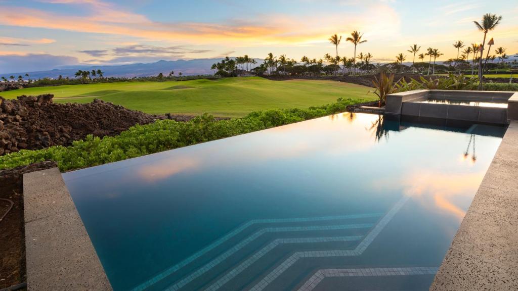ワイコロアにあるELEGANT ESCAPE Elegant 4BR Laulea Home with Pool and Ocean Viewのゴルフコースを背景にしたインフィニティプール