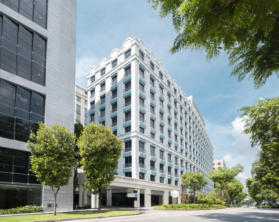 un edificio alto y blanco con árboles delante en Adina Serviced Apartments Singapore Orchard, en Singapur