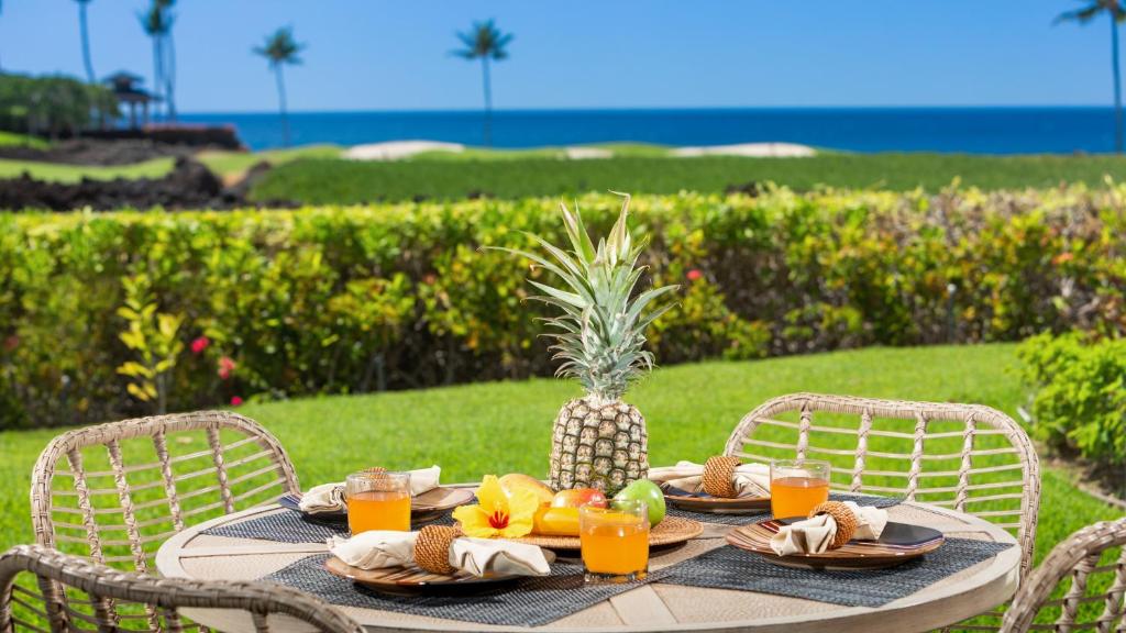 une table avec un ananas et des fruits dessus dans l'établissement THE POINT Contemporary 2BR Mauna Lani Point Home with Ocean View, à Waikoloa