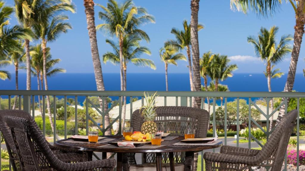 a table with fruit on a balcony with palm trees at OCEAN PALSM VILLA Refined 3BR Waiulaula Home with Stunning Ocean Views in Hapuna Beach