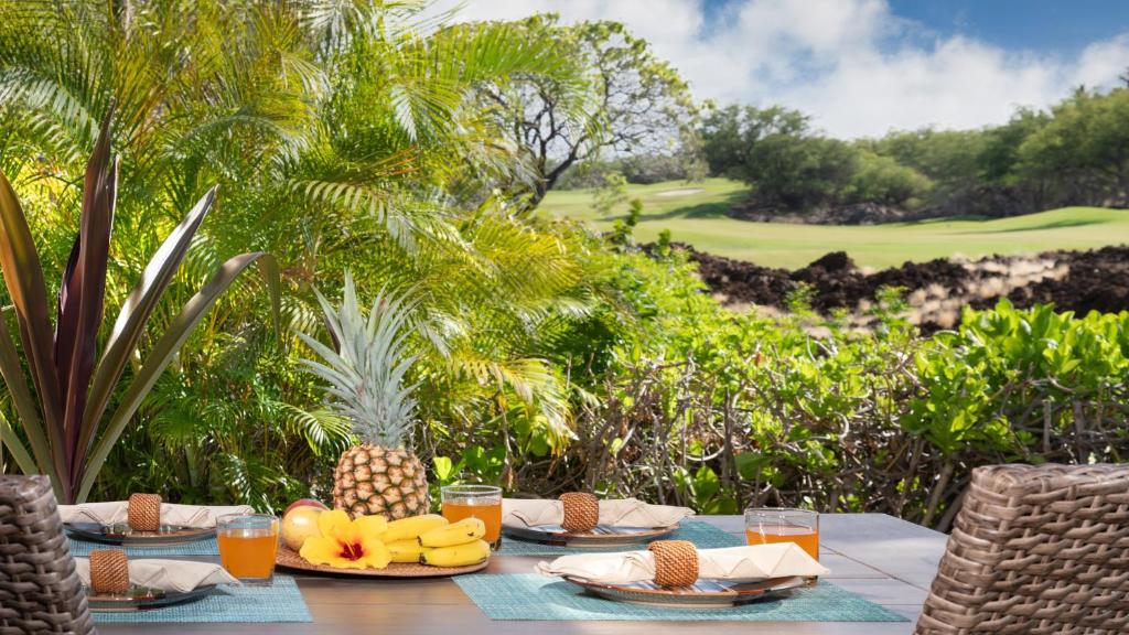 a table with plates of food and fruit on a golf course at ORCHID VILLA Inviting Fairways 3BR with Bikes and Private Beach Club in Waikoloa