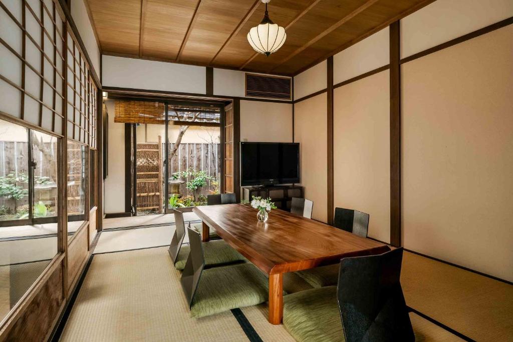 uma sala de jantar com uma mesa de madeira e cadeiras em Hatoba an Machiya House em Quioto