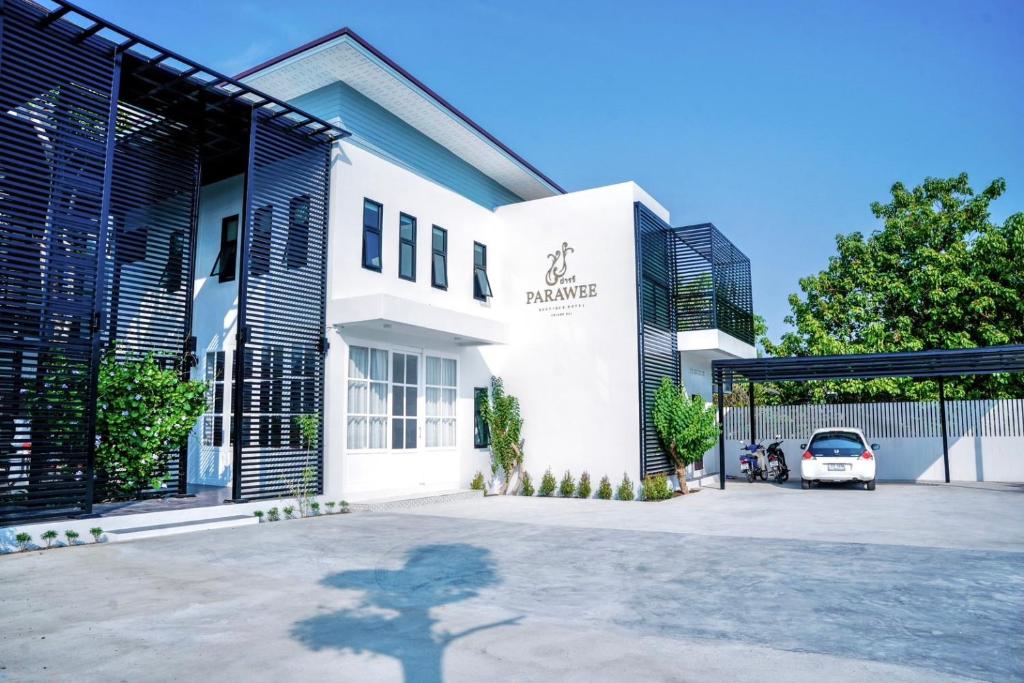 um edifício branco com um carro estacionado num parque de estacionamento em โรงแรม ปารวี บูทีค เชียงราย (Parawee Boutique Hotel) em Chiang Rai
