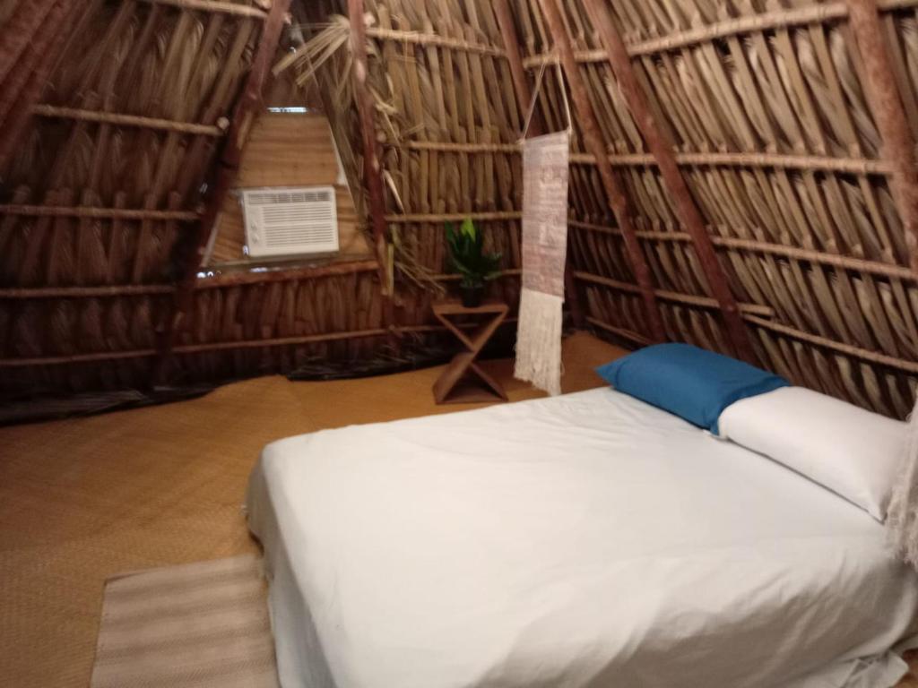 a bedroom with a bed in a straw hut at El Puente in El Paredón Buena Vista