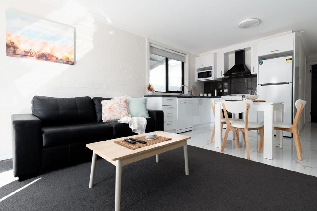 a living room with a black couch and a table at Riverside Gem with Parking & WiFi in Alanvale