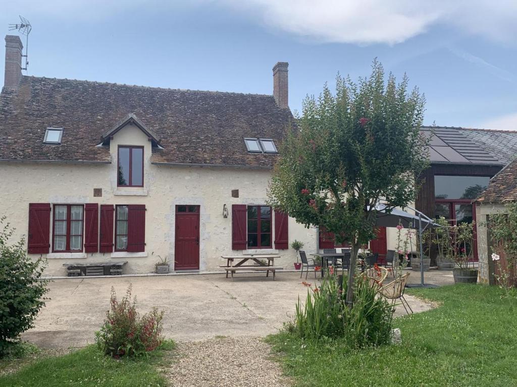 une maison avec des portes rouges et une table de pique-nique dans l'établissement Gîte avec Spa, Sauna, Jardin et Jeux - Proche Châteaux de la Loire - FR-1-491-397, à Mont-près-Chambord
