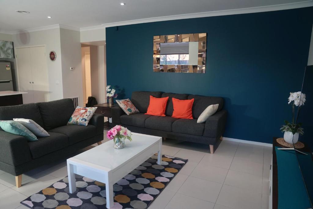 una sala de estar con 2 sofás y una pared azul en Designer Decor Home with 8Beds at Williams Landing, en Laverton