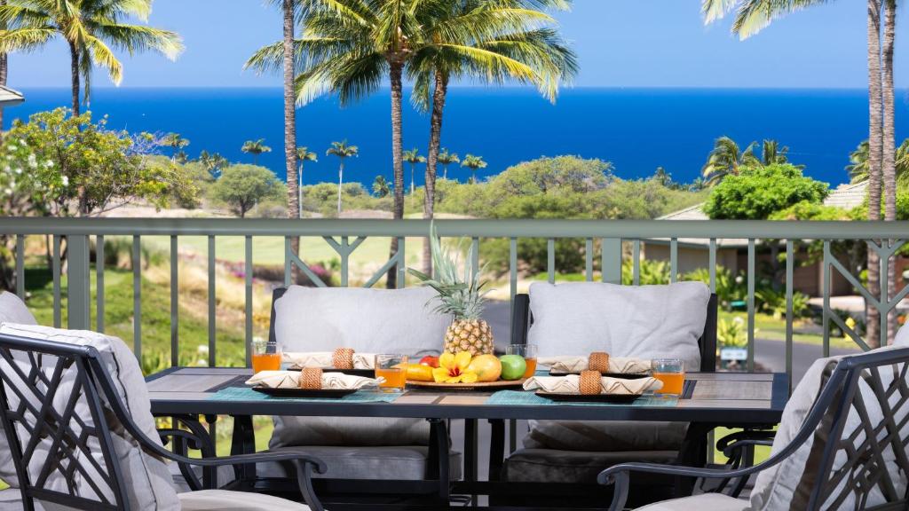 a table with fruit on a balcony with palm trees at A Sea-nic Escape Scenic 3BR Waiulaula Home with Ocean View in Hapuna Beach