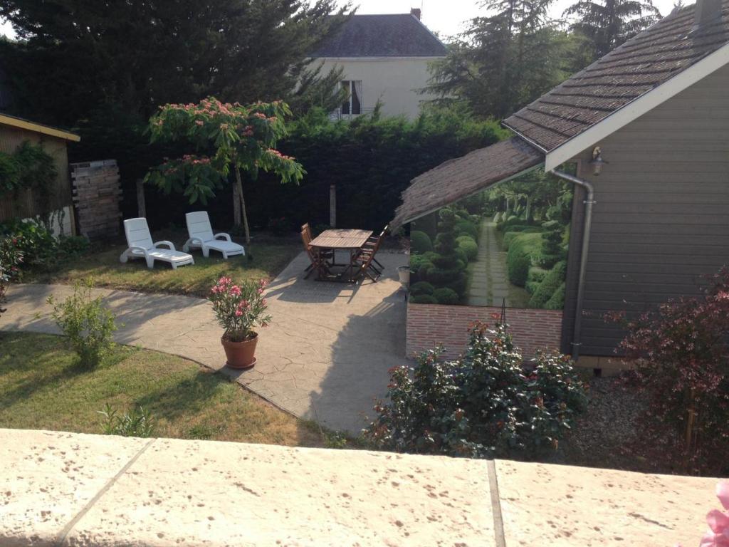 een achtertuin met een tuin met twee stoelen en een tafel bij Gîte confortable près du Zoo de Beauval, avec jardin - FR-1-491-428 in Meusnes
