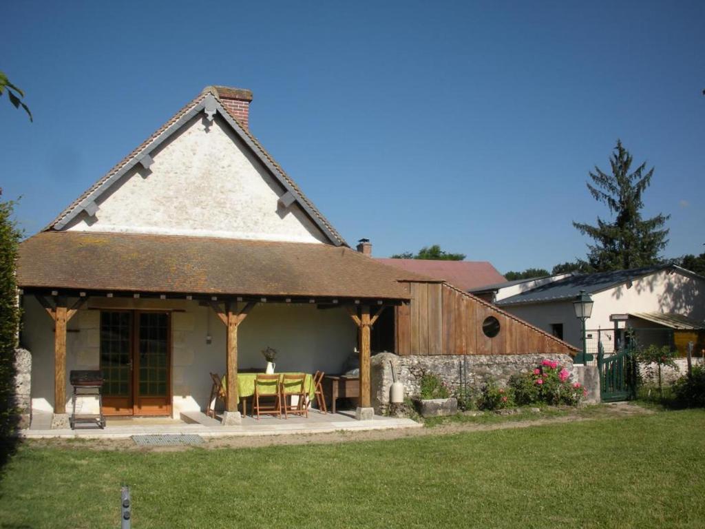 une maison avec une terrasse couverte et une table dans une cour dans l'établissement Gîte Fresnes , 3 pièces, 5 personnes - FR-1-491-440, 