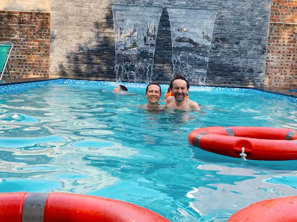 dos personas en una piscina con una fuente en Tam Coc Golden Sky Homestay, en Ninh Binh
