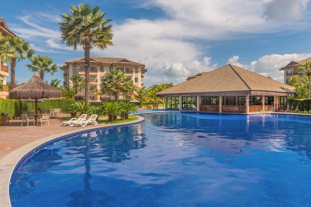 einen Pool in einem Resort mit Palmen und Gebäuden in der Unterkunft Vg Sun Condominio pe na areia estilo resort in Caucaia