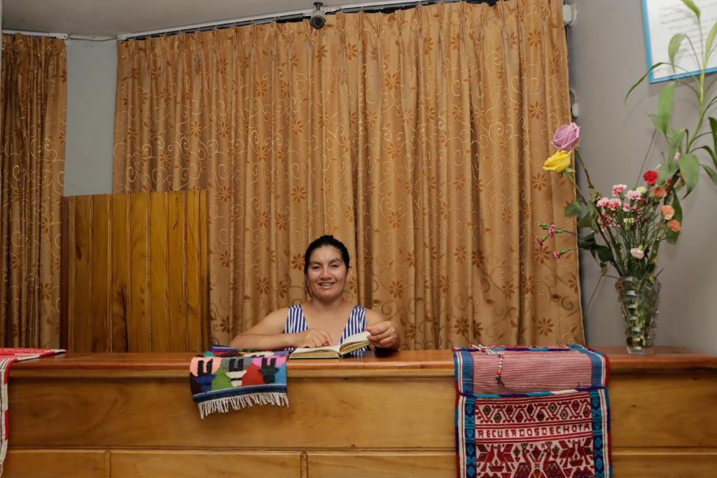 una mujer sentada en un escritorio con un libro en Irigoin Hospedaje, en Nueva Cajamarca