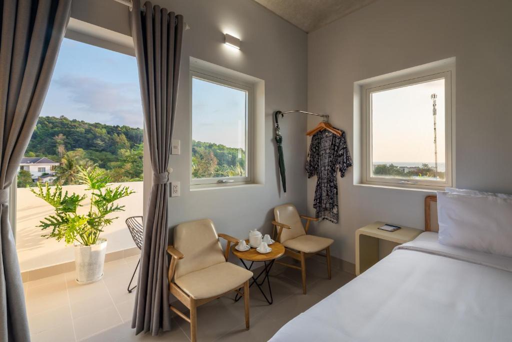 1 dormitorio con 1 cama, 1 mesa y 2 sillas en The Up Phu Quoc, en Phu Quoc