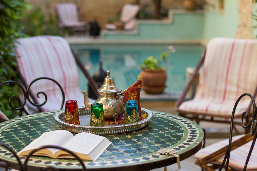 a table with a tea pot and a book on it at Riad Norma in Fès