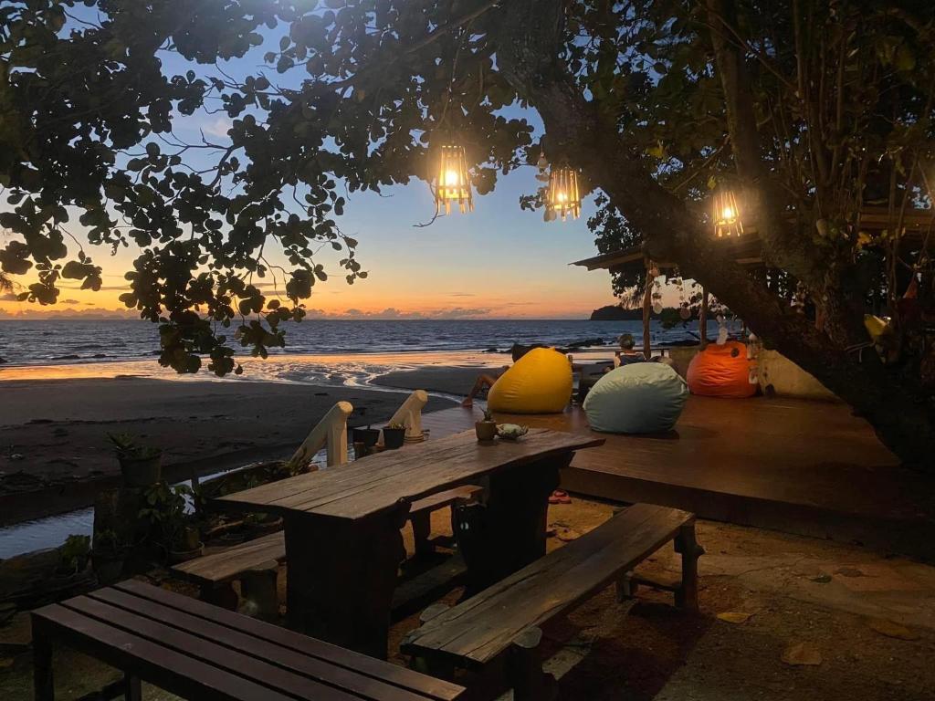 a picnic table on the beach with a sunset at Coconut Lanta Resort @Klong Dow beach in Krabi town