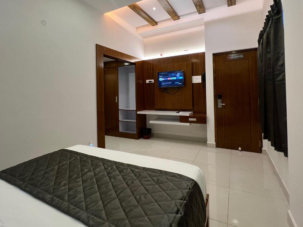1 dormitorio con 1 cama y TV en Le Hotel Host en Tiruchchirāppalli