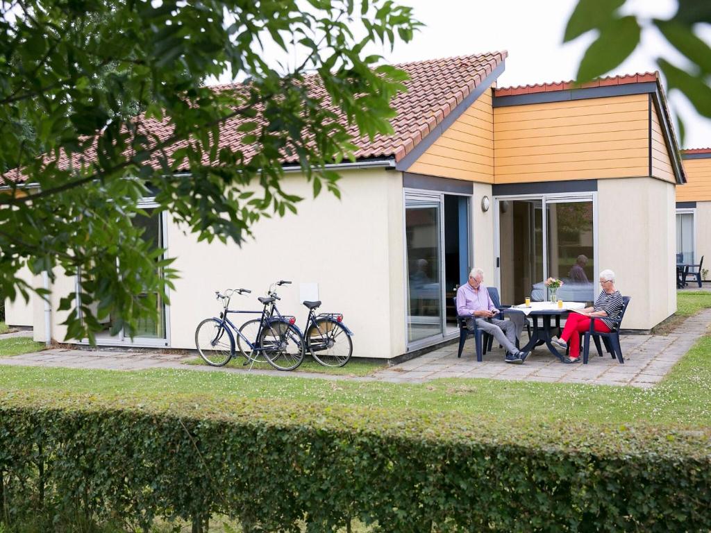 dois homens mais velhos sentados numa mesa fora de uma casa em Enjoy a 6-person bungalow em Zevenhuizen