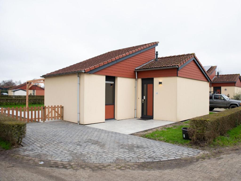 uma casa com um telhado vermelho e uma entrada em Luxury bungalow for 6 people em Zevenhuizen