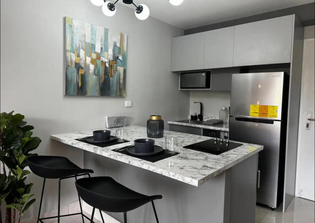 a kitchen with a counter with stools and a refrigerator at Lujoso y cómodo apartamento in Tegucigalpa