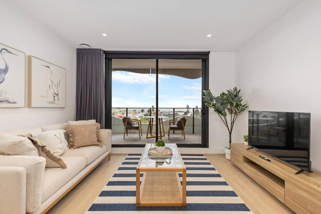 a living room with a couch and a tv at Sea View 2BR w Best Rooftop Pool in Melb! in Melbourne