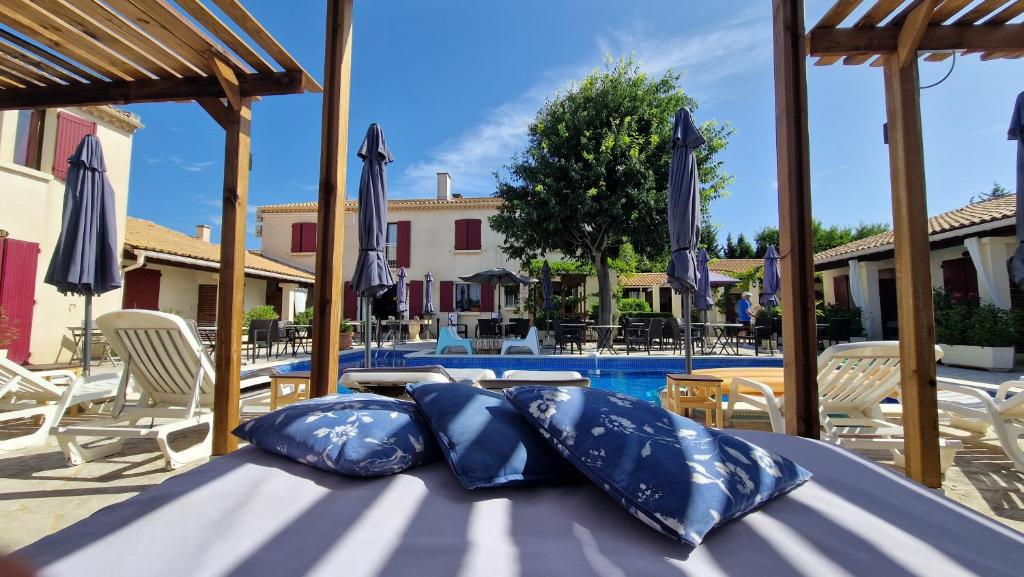 a table with pillows on it next to a swimming pool at Hôtel Le Mas Des Amandiers in Graveson