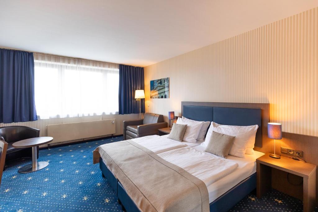 ein Hotelzimmer mit einem großen Bett und einem Stuhl in der Unterkunft Novum Hotel Imperial Frankfurt Messe in Frankfurt am Main