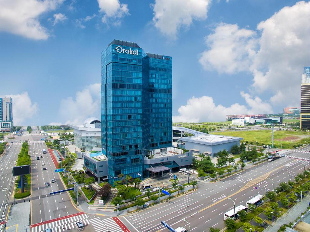 a tall blue building with a sign on it next to a road at Orakai Songdo Park Hotel in Incheon