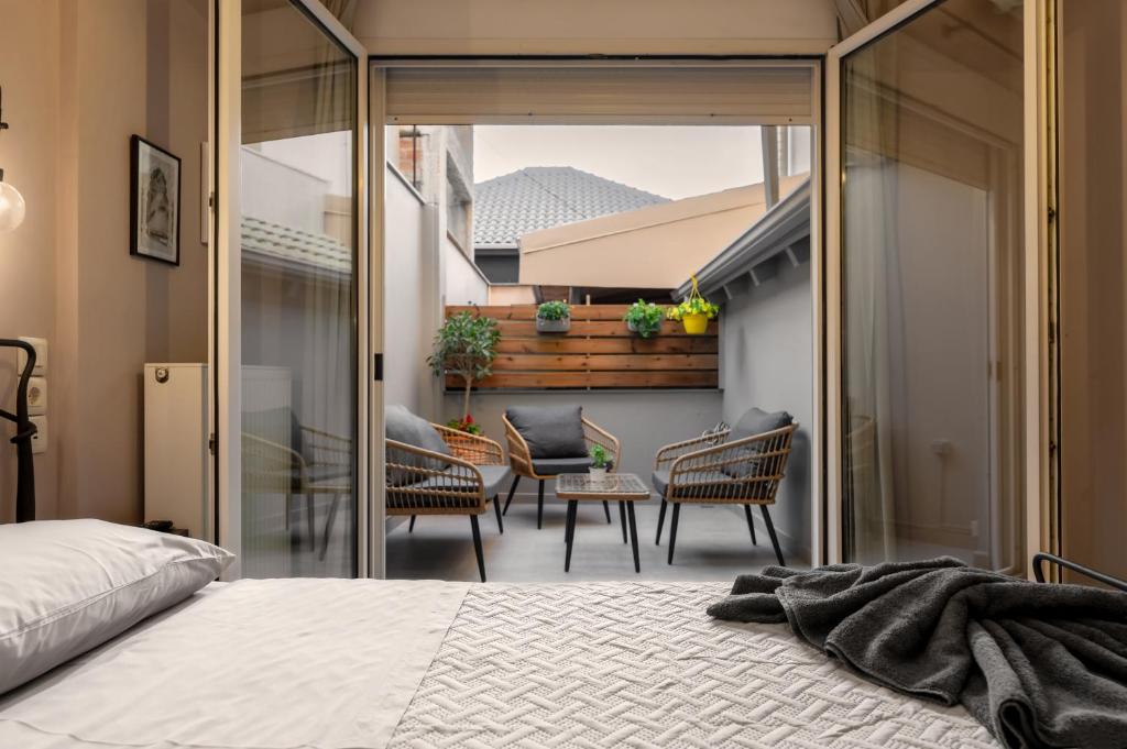 1 dormitorio con 1 cama y balcón con sillas en City Lights Preveza, en Preveza