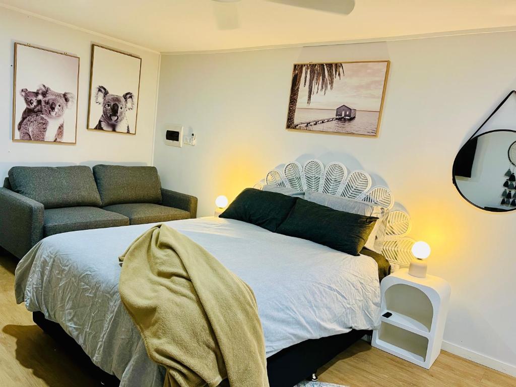 um quarto com uma cama e um sofá em 2Bays Studio- Walk to 2 Beaches! Perfect Location with Private Courtyard & BBQ em Nelson Bay
