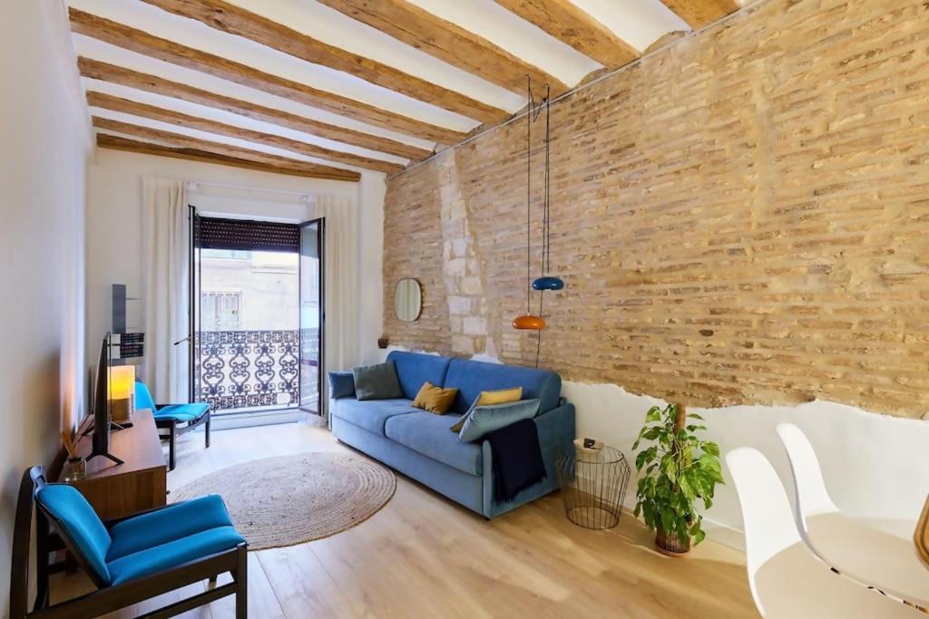 a living room with a blue couch and a brick wall at Precioso apartamento en la calle Estafeta! in Pamplona