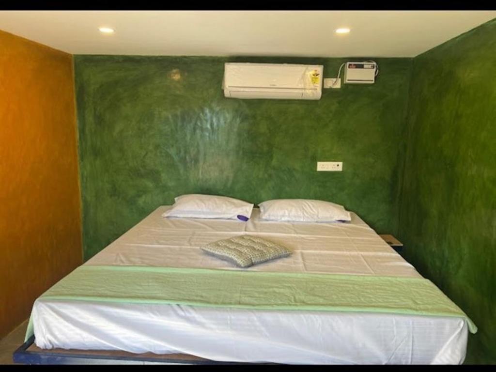 a bedroom with a green wall with a bed at Nature Zone Resort in Puducherry