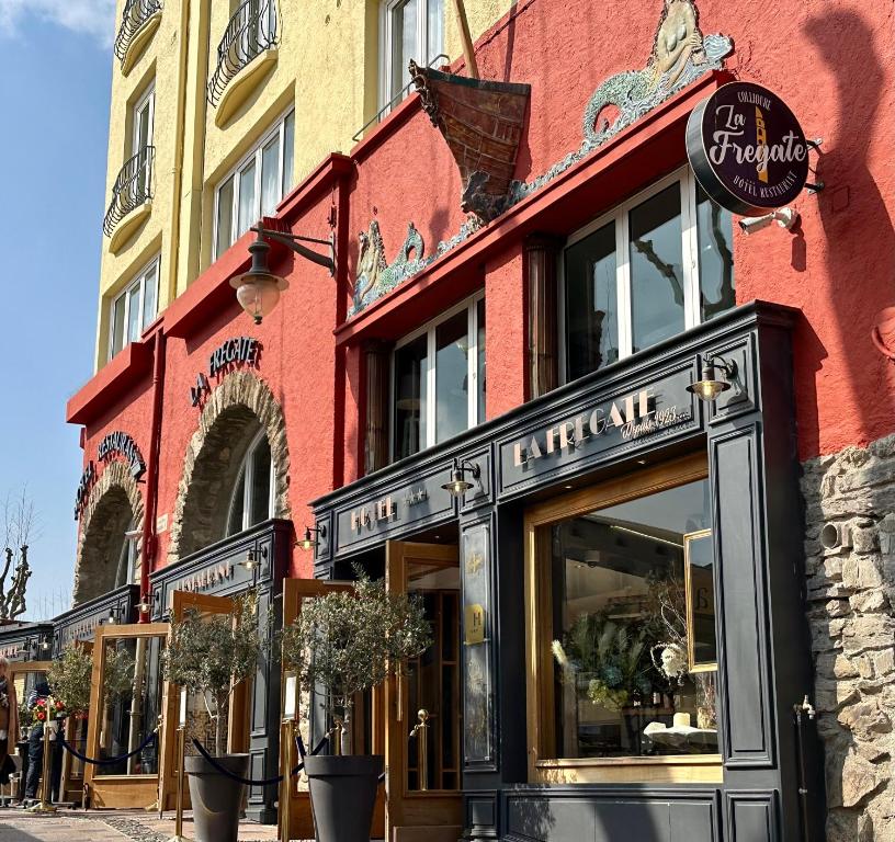 a store front of a red building on a street at La Fr&eacute;gate in Collioure
