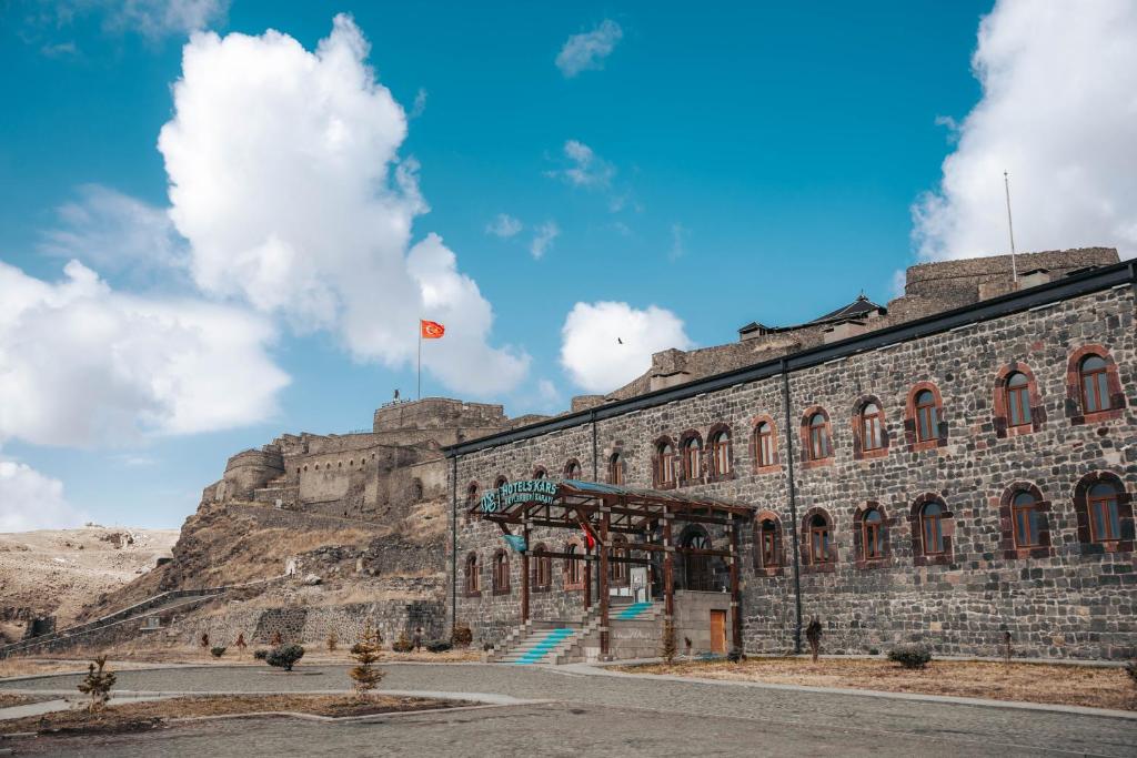 un edificio con una bandera en la cima de una montaña en Ve Hotels Beylerbeyi Sarayı, en Kars
