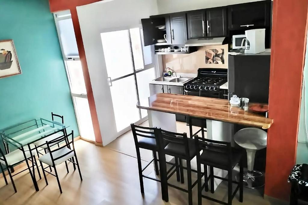 a kitchen with a counter with chairs and a stove at Casa Magro depto para 6 in Oaxaca City
