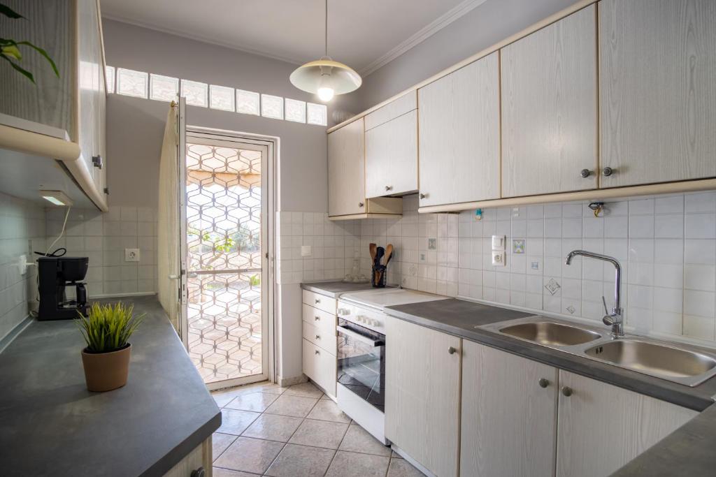 a kitchen with white cabinets and a sink and a window at Stefano's Home in Potokáki