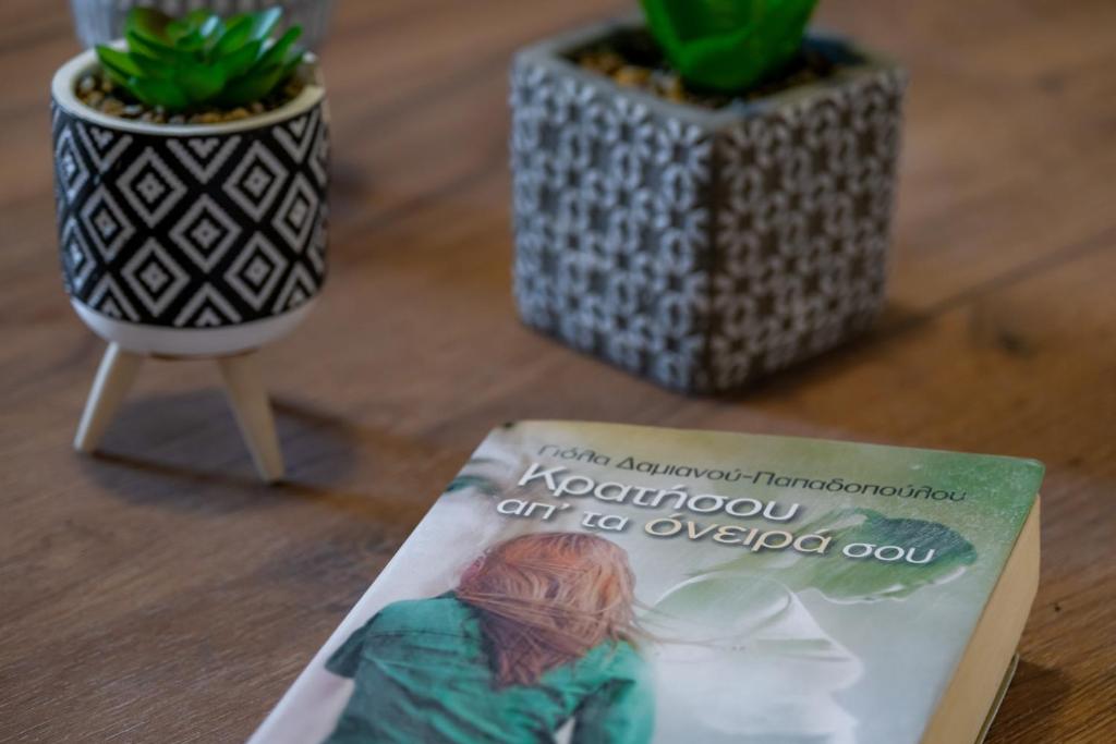a book sitting on a table next to two potted plants at Stefano's Home in Potokáki