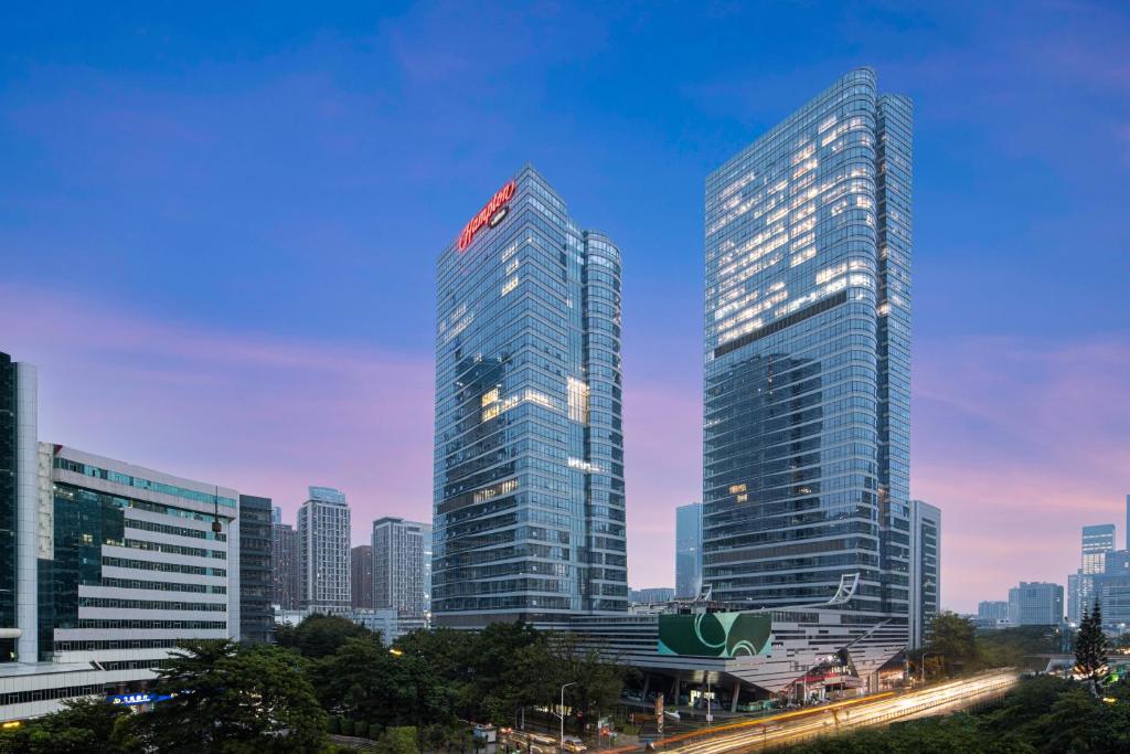深セン市にあるHampton by Hilton Shenzhen Nanshan Science and Technology Parkの夕暮れ時の都市の高層ビル2棟