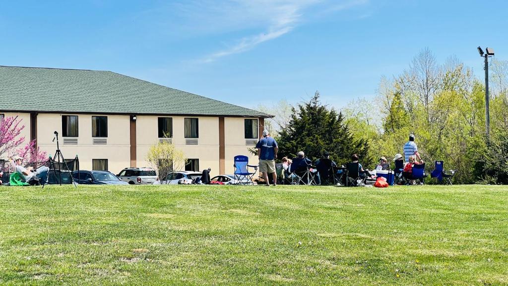 a group of people standing in a field near a house at Americas Best Value Inn Pinckneyville in Pinckneyville