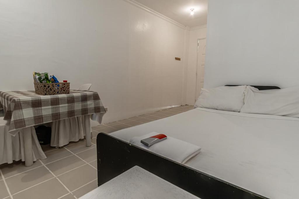 One Alo Hotel and Resort في Manaoag: غرفة بيضاء مع سرير وطاولة