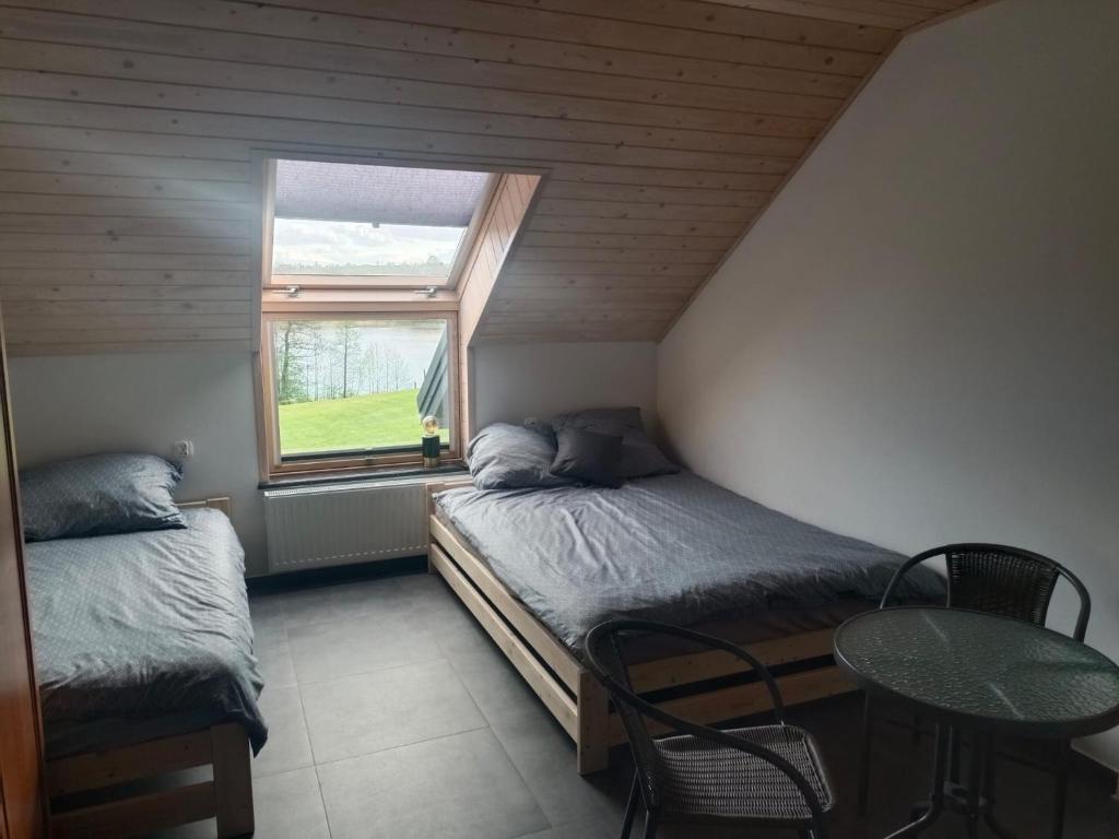 um quarto com 2 camas, uma mesa e uma janela em Agroturystyka Żuczek em Okuniowiec