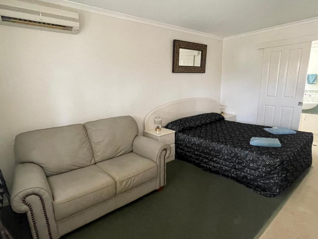 a living room with a bed and a couch at Warrego Motel in Charleville